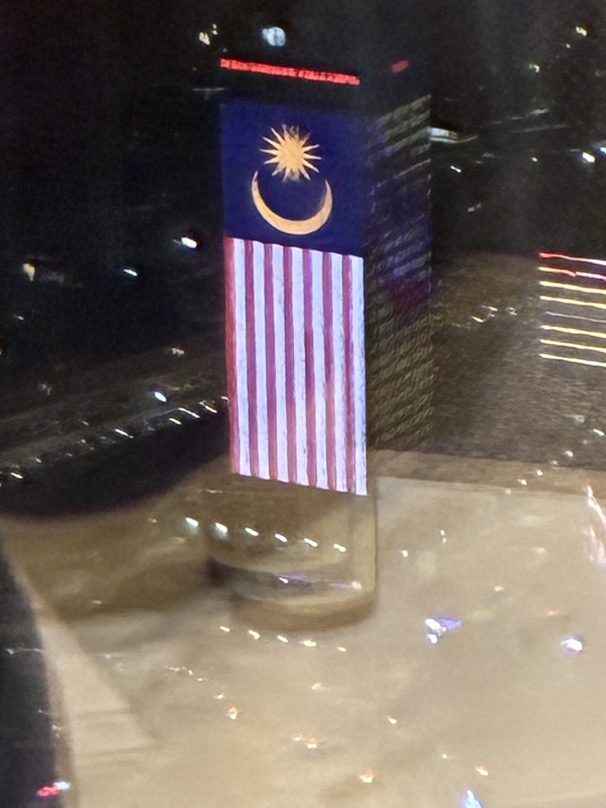 夜、壁面いっぱいにマレーシア国旗が映るビル